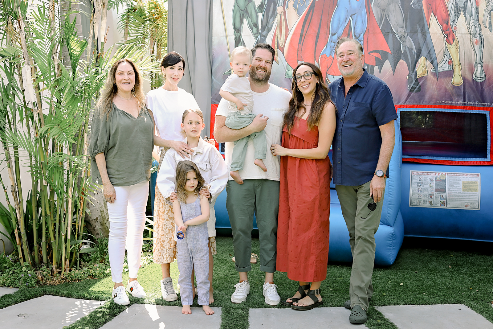 Group of parents and kids smiling in front of the bounce house.