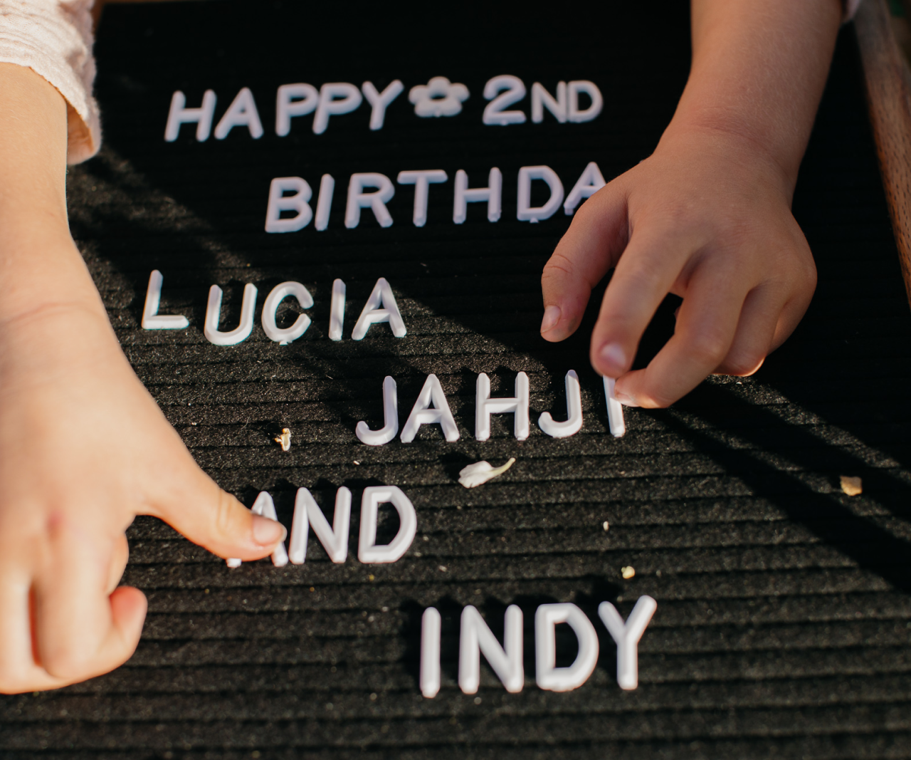 Close-up of a kids' hands adjusting letters on a letter board.