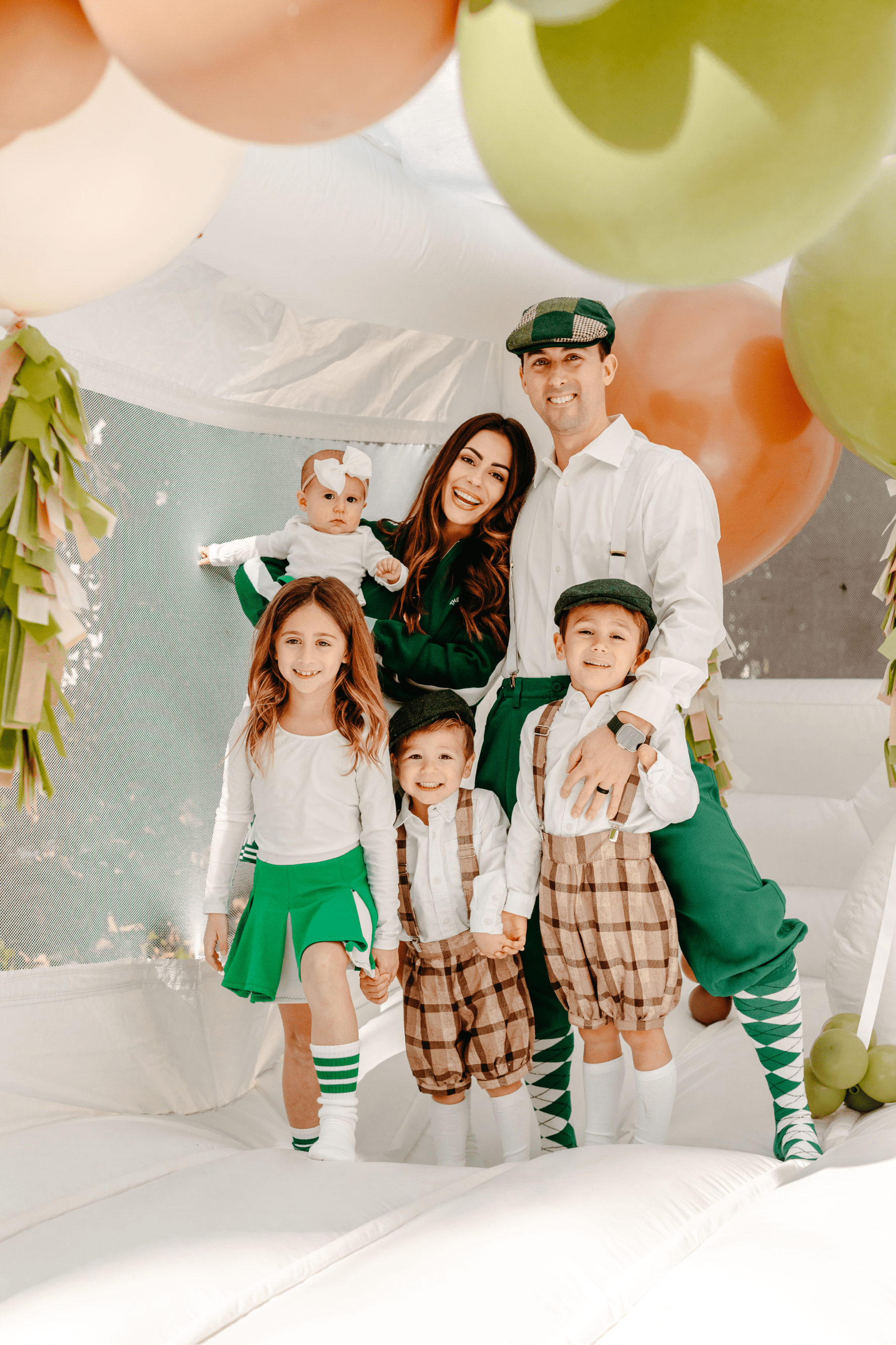 Family dressed in golf-themed attire posing and smiling while standing inside of the bounce house.