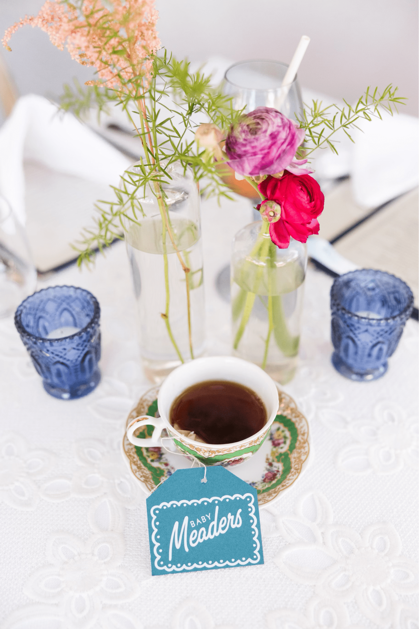 A cup of tea with a personalized tea bag and flowers in the background.