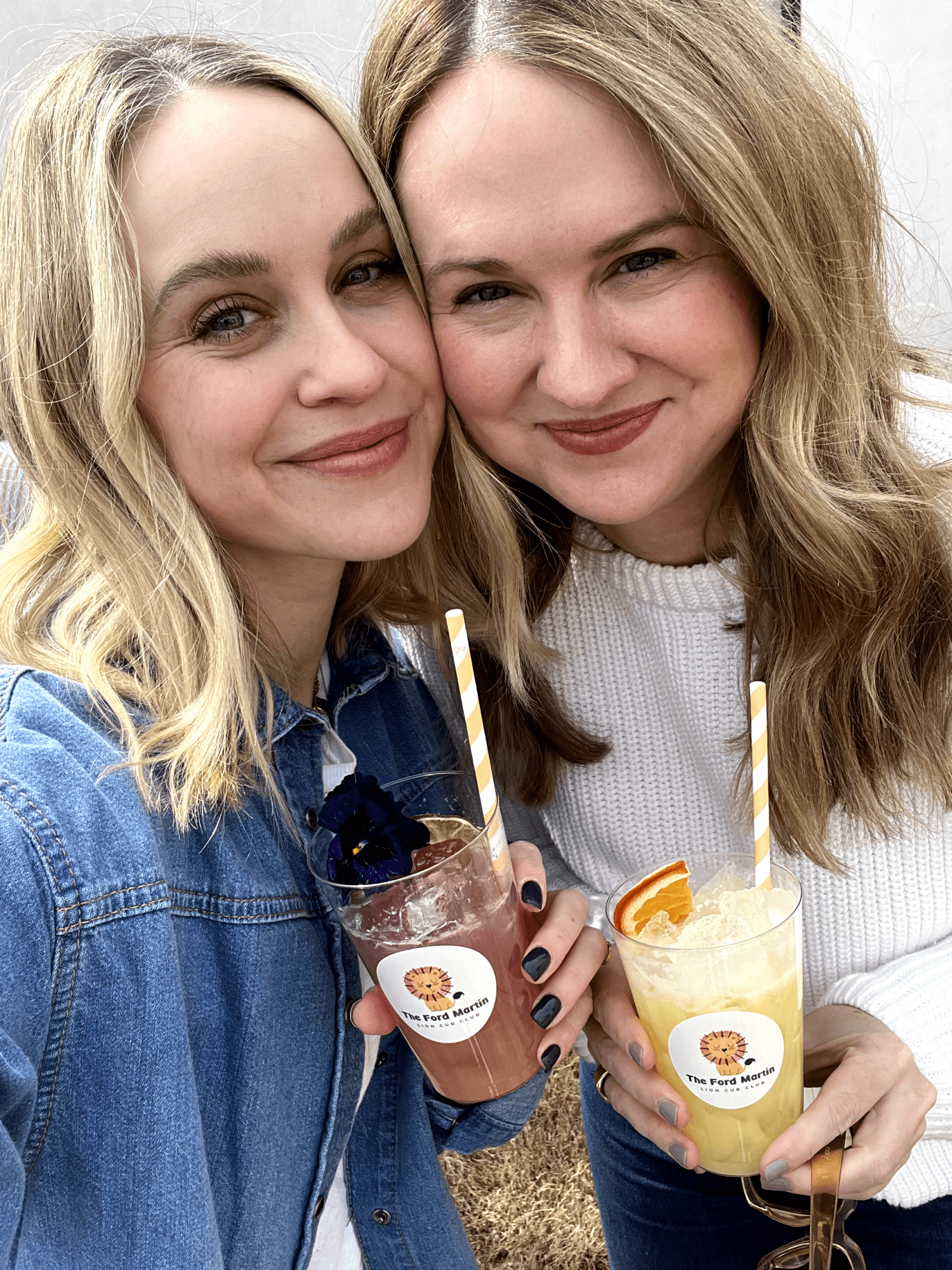 A selfie of two women holding personalized cocktails.