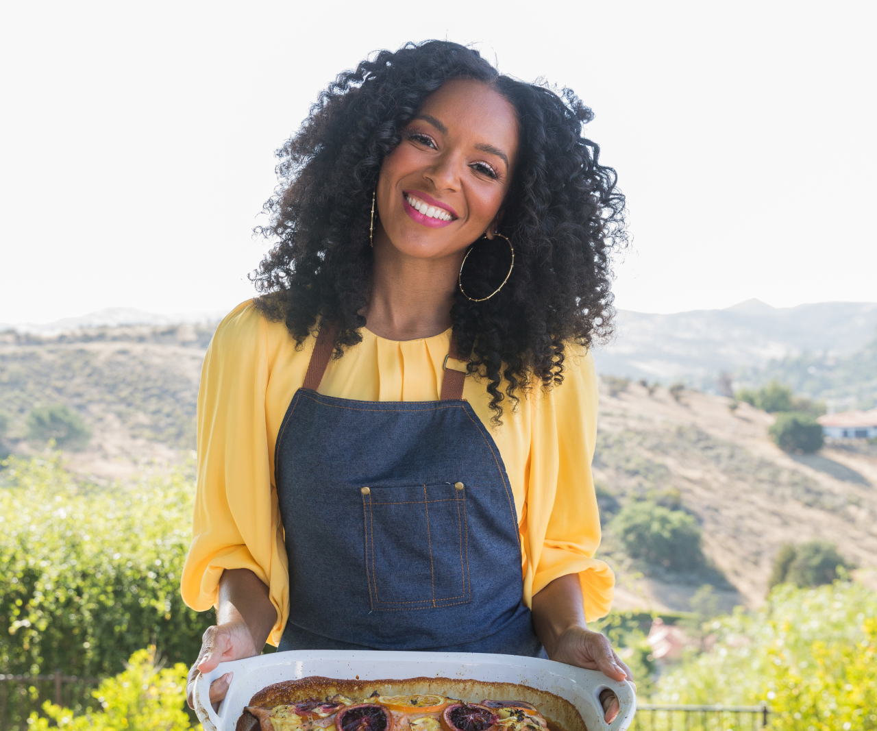 Lizzy Mathis smiling while holding a casserole pan of salmon.