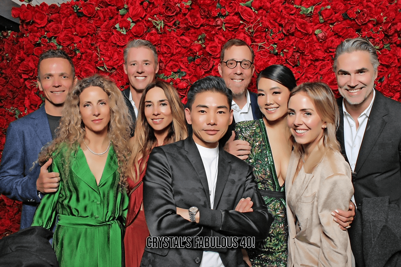 A picture of people in front of a backdrop made of roses.