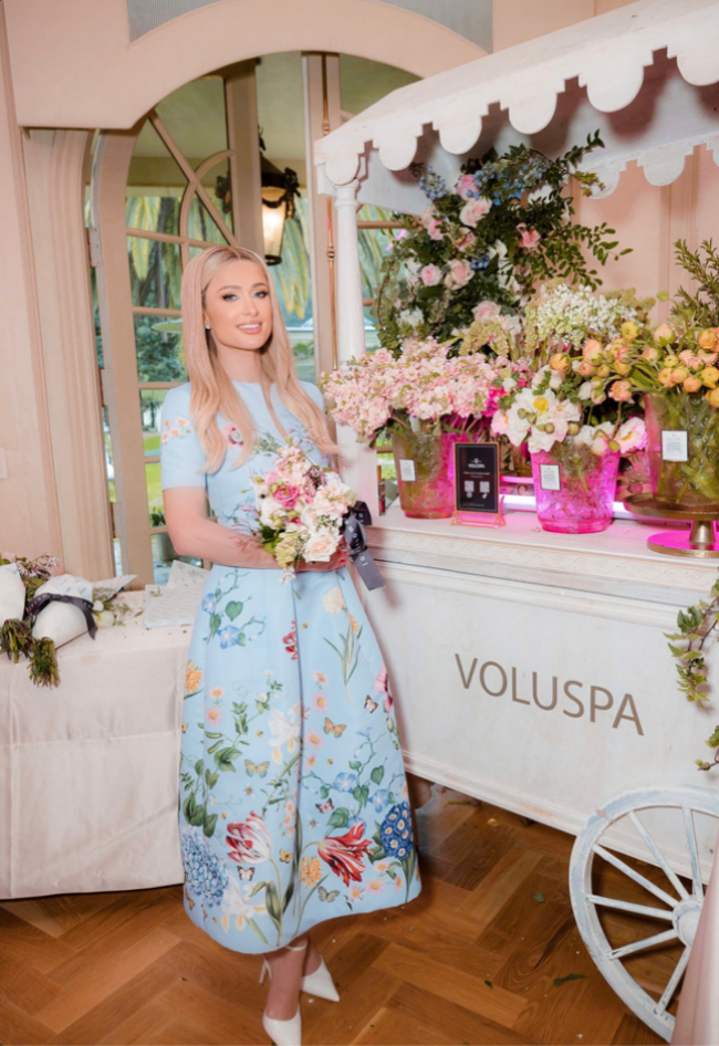 Paris Hilton holding a bouquet next to a cart full of flowers.