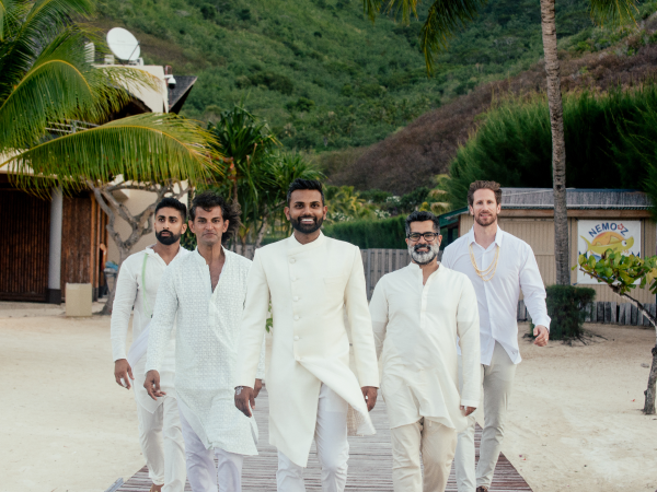 Five men wearing all white walking down a boardwalk.