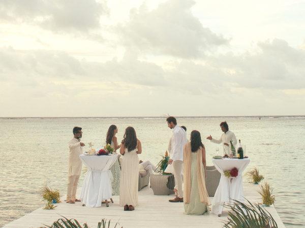 Wedding guests enjoying drinks and food on a small pier on the water.