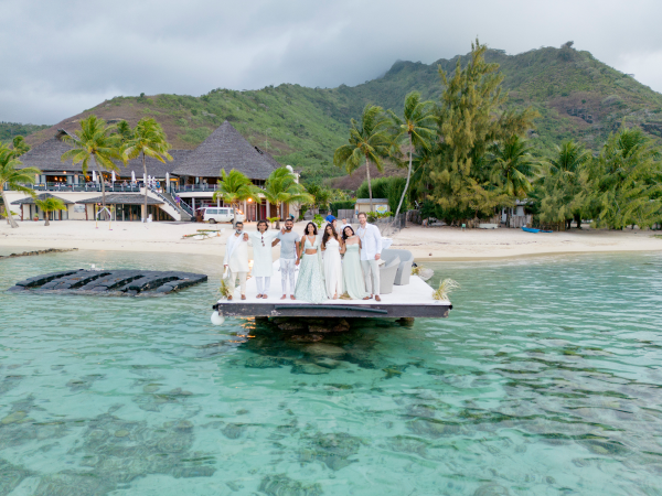 A drone image of Priya, Sumanth, and their wedding guests posing for a photo on the pier.