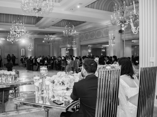 A black and white image of the ballroom full of guests sitting at their tables.