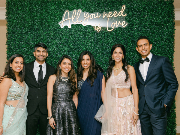 A group of people posing in front of a backdrop that says "All you need is love."