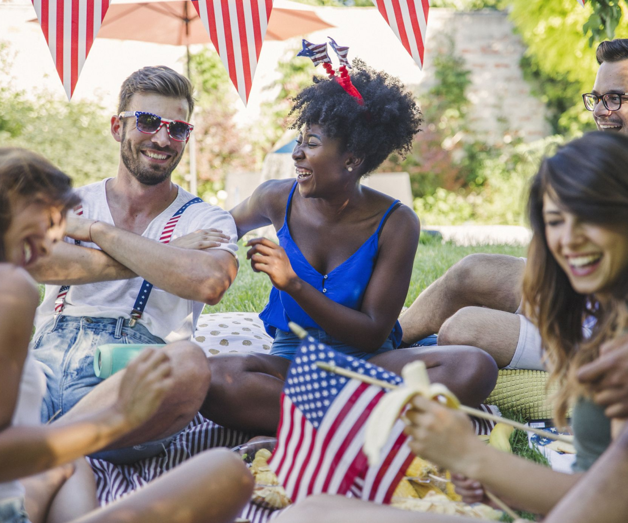 People sitting on the ground laughing and wearing red, white, and blue.