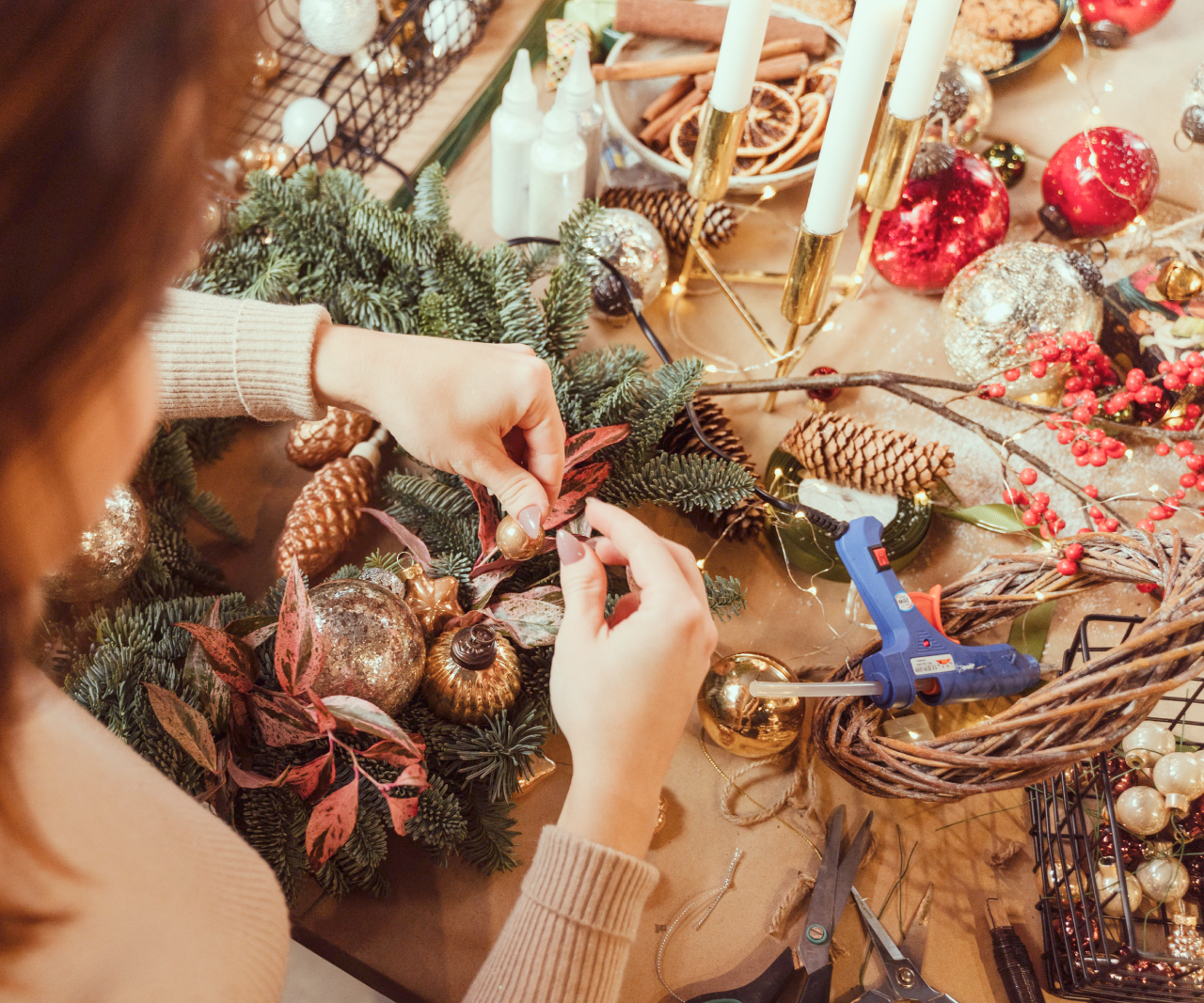 Woman sitting at a table surrounded by holiday crafting materials.