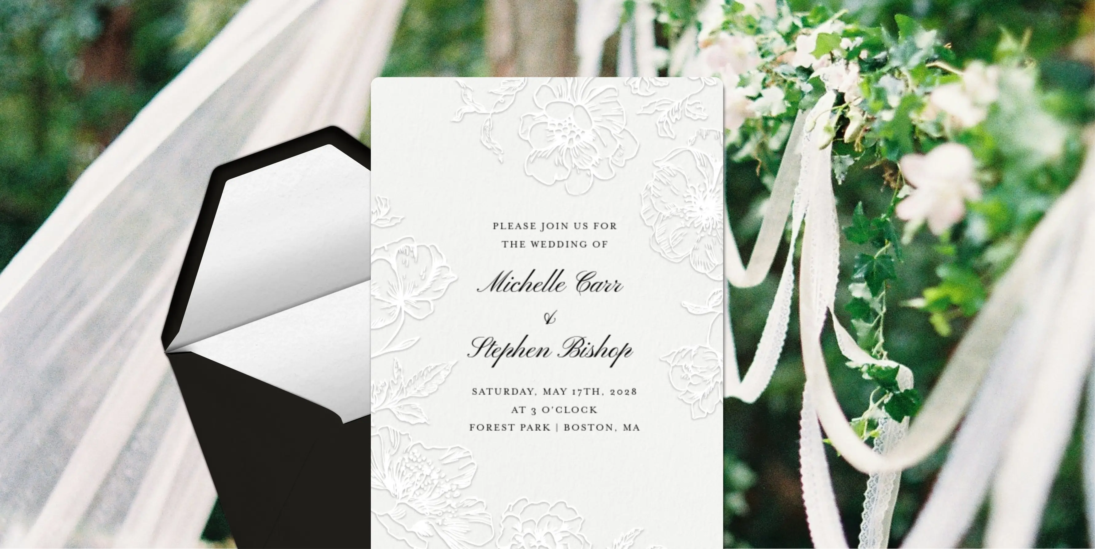 A white Invitation with floral lace details and black script text. 
