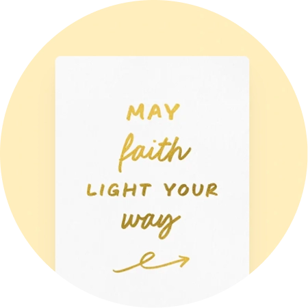 A greeting card featuring the text "May faith light your way" in gold foil against a white, paper-like textured background.
