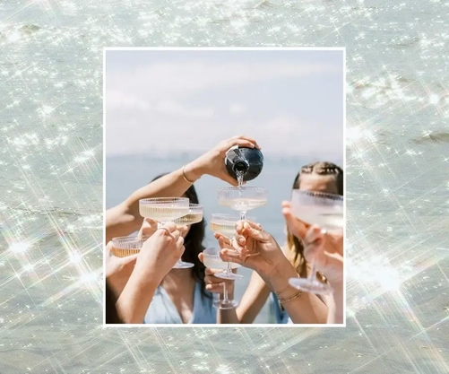 A photo of champagne being poured into cups set against a shimmering background.