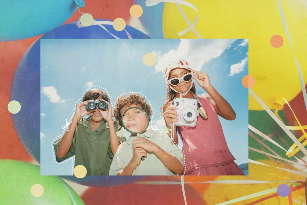 A photo of three kids posing outdoors holding binoculars, a magnifying glass, and an instant camera, set against a colorful balloon backdrop.