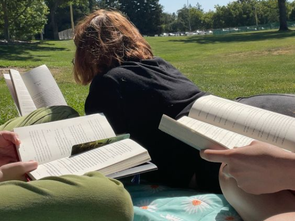 A group of people reading books together in a park.
