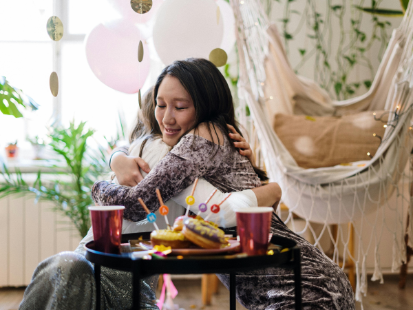 Two women hugging each other in someone's home.