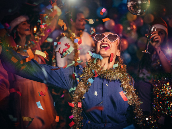 Woman dancing at a holiday party with a disco ball and confetti.
