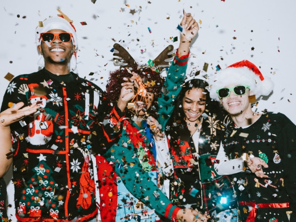 People dressed up in Santa hats posing for a photo with confetti everywhere.