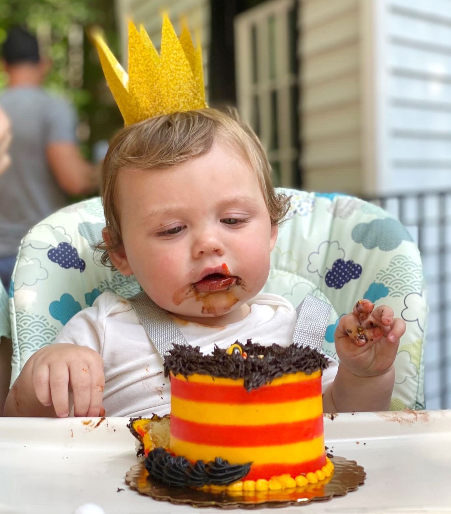 Child wearing a crown while eating a chocolate cake.