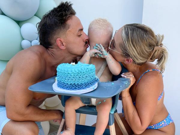Crew's parents kissing him as he eats cake.