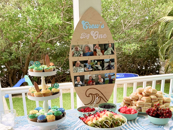A surfboard-shaped photo display and table full of food.