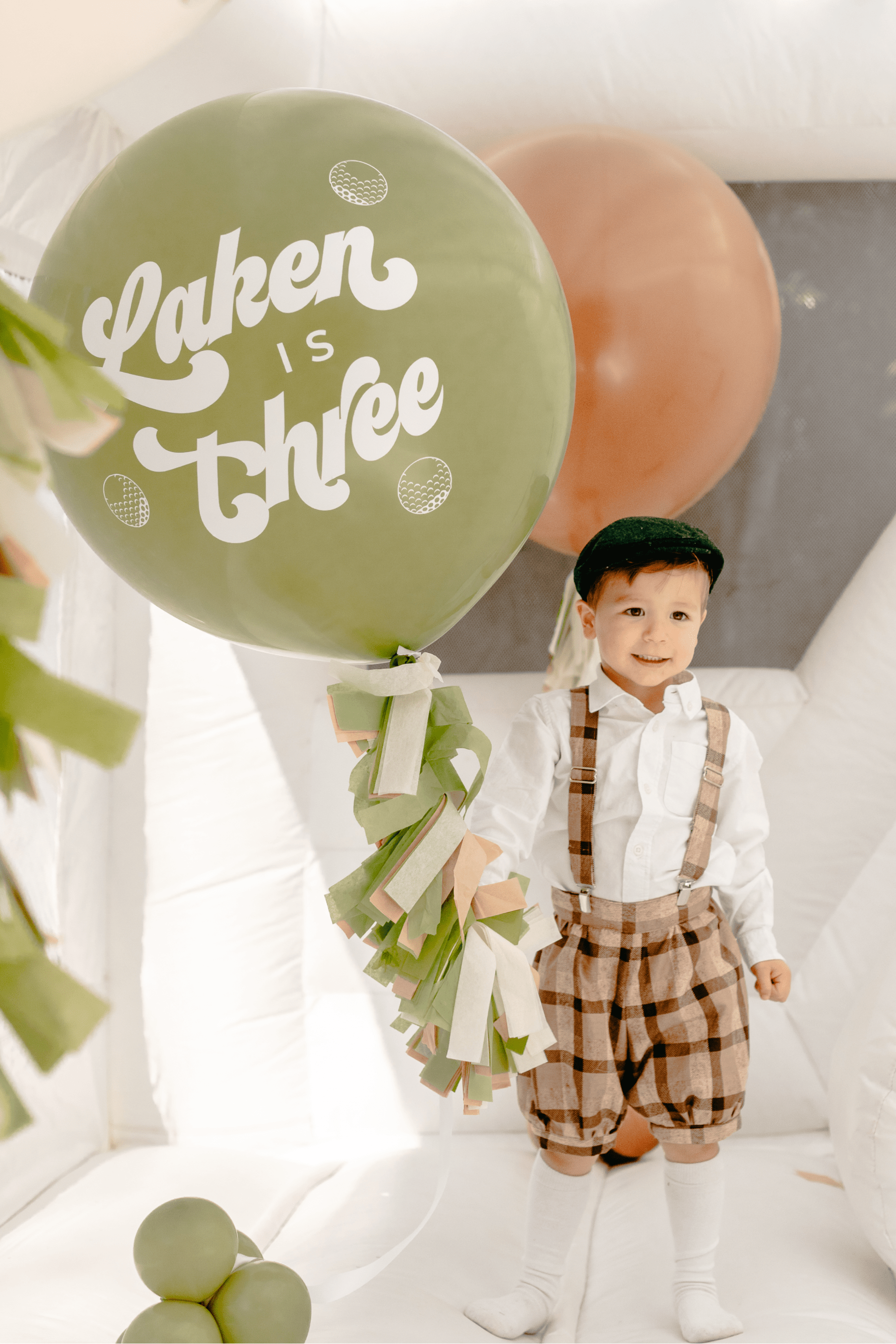 The birthday boy holding a personalized balloon while standing in the bounce house.