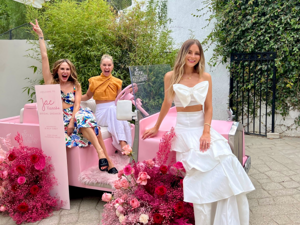 Three women posing in a pink vintage car.