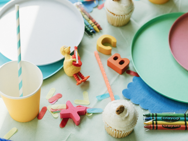 Big Bird figurine next to cupcakes and crayons.